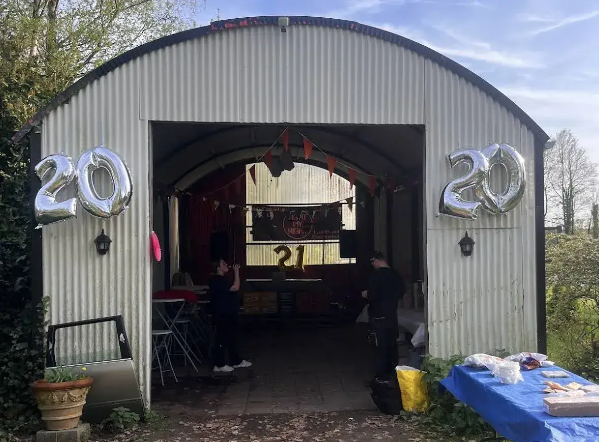 Feestelijke ingang van een loods met zilveren 20-ballonnen en sfeerlicht