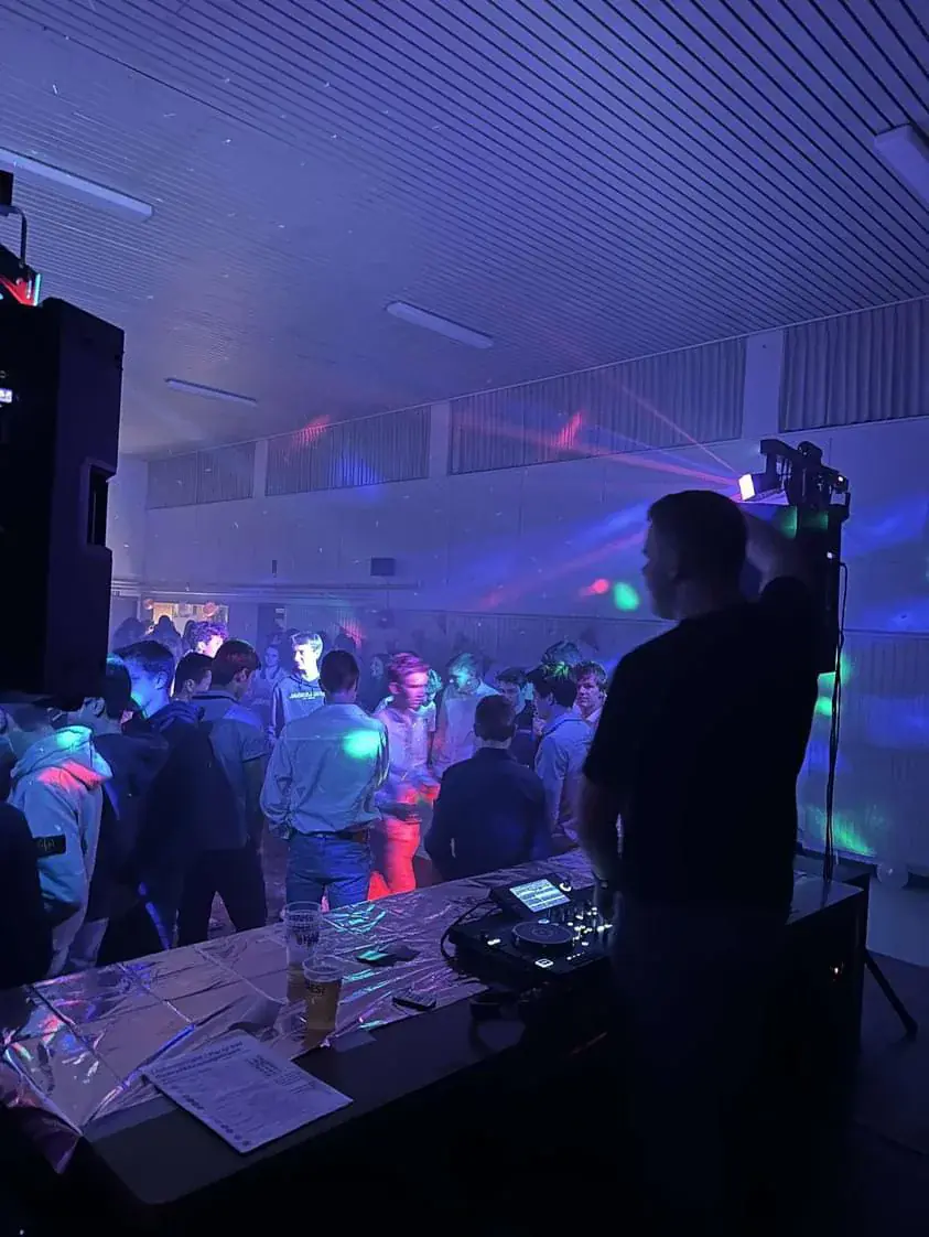 DJ achter de booth met publiek en lasers in een feestzaal in Turnhout