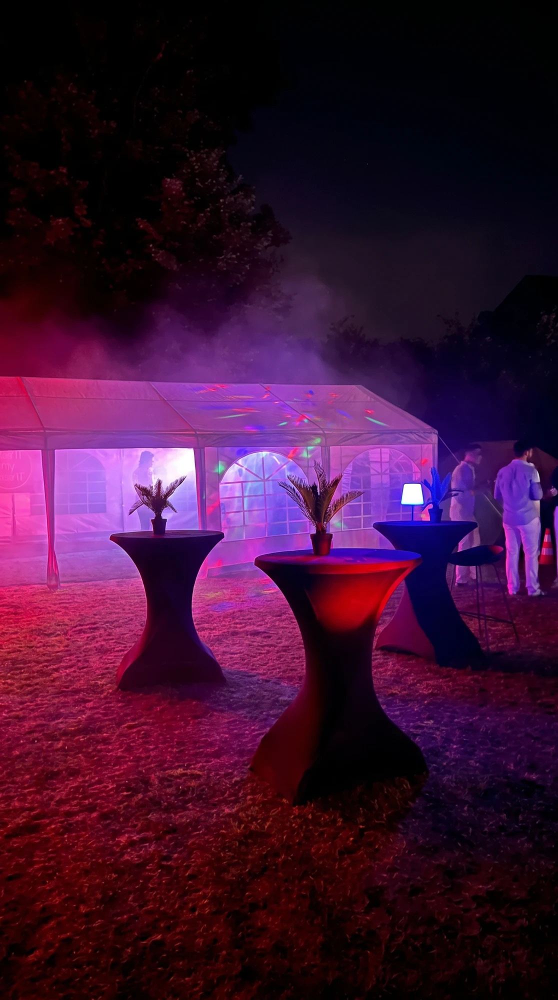 Statafels met zwarte stretchhoezen en sfeerverlichting in een tent