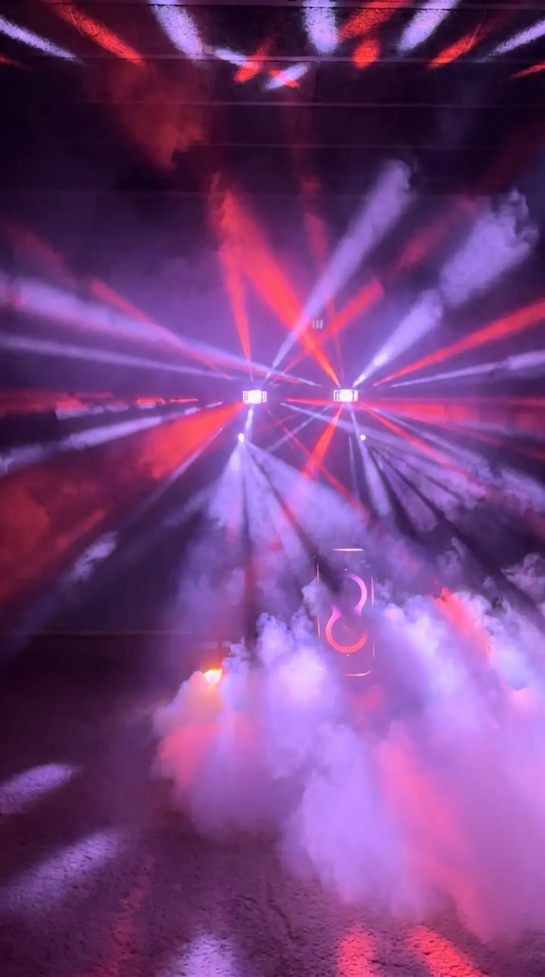 Moving heads met paarse en rode lichtstralen door lage rook