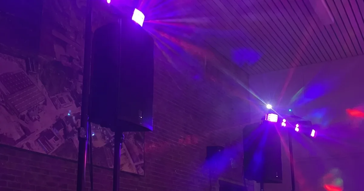 DJ-podium met speakers, lichtbarren en paarse feestverlichting