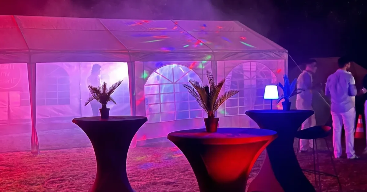 Statafels met zwarte stretchhoezen en sfeerverlichting bij een tent