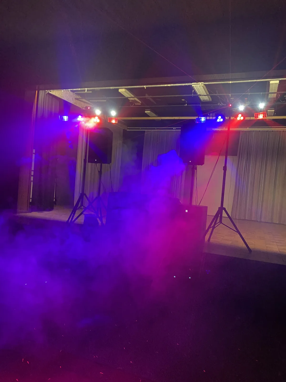 Speakers op statieven op een podium in paarse rook